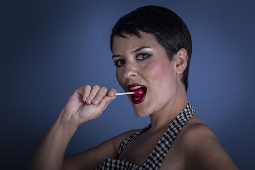 happy young woman with lollypop in her mouth on blue background