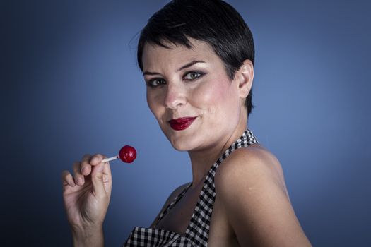 happy young woman with lollypop in her mouth on blue background