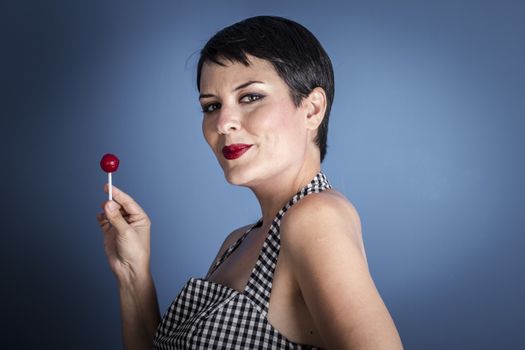 happy young woman with lollipop in her mouth on blue background