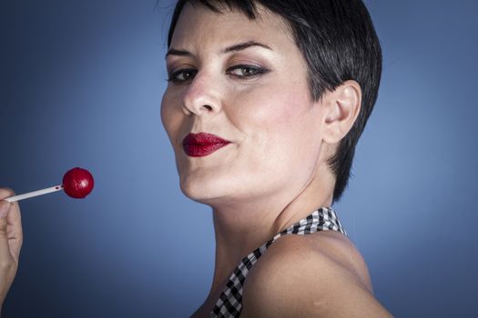 Diet, happy young woman with lollypop in her mouth on blue background