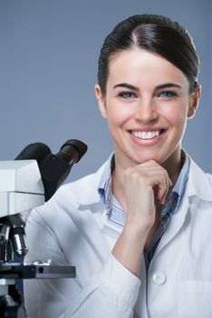 Attractive female researcher smiling with hand on chin.