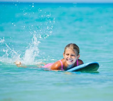 Summer vacation - Happy cute girl having fun with surfboard in the ocean