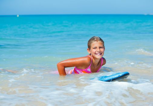 Summer vacation - Happy cute girl having fun with surfboard in the ocean