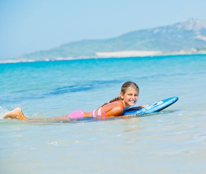Summer vacation - Happy cute girl having fun with surfboard in the ocean
