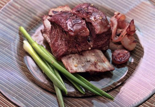 Roast red beef meat bbq bloc served on black plate with green chives