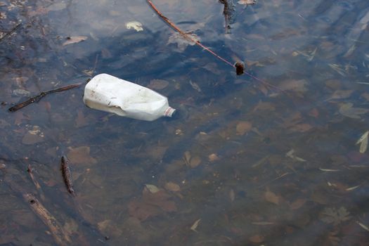 Bottle floating in a pond, pollution and litter.