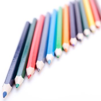 Bunch of sharpened wooden colourful pencil crayons in the colours of the spectrum or rainbow on a white background symbolising art and creativity