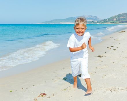 Smiling cute boy runs along the tropical beach.