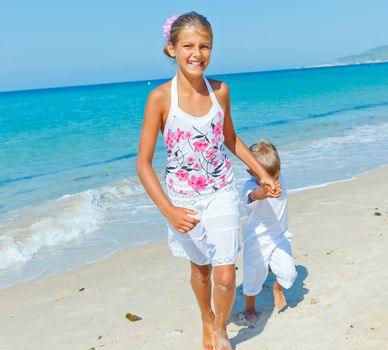 Adorable happy boy and girl runs along beach vacation