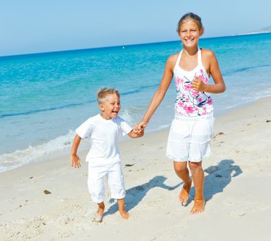 Adorable happy boy and girl runs along beach vacation