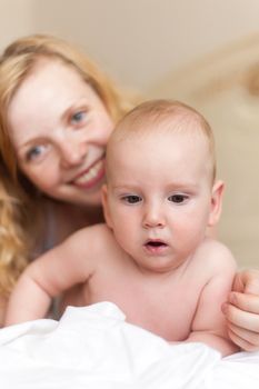 Mother with her baby playing on the bed