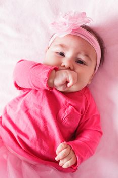 Three month old baby girl is sucking her fist