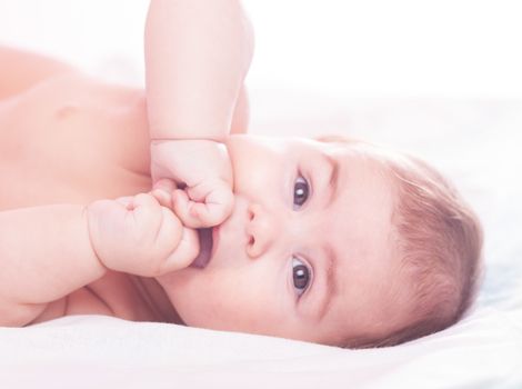 Five month old baby is sucking her fists. Close up face