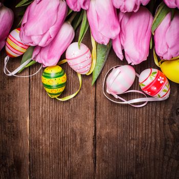 Tulips and eggs border over wooden backdrop. Easter decorations.