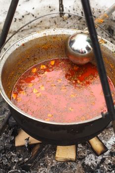 Traditional hungarian dish - bogracs goulash, stewed meat and vegetables in cauldron, outside in winter fireplace