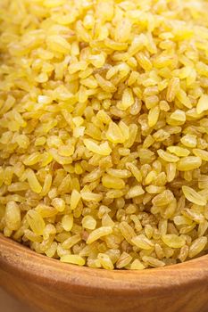 Raw bulgur in a wooden bowl on the table