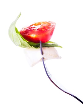 Caprese salad ingredients on the fork isolated on white