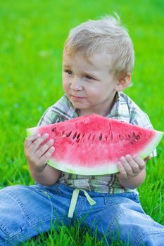 Kid with slice of watermelon, outdoors eating, picnic