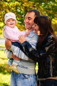 Happy family outdoor - mother, father and daughter are smiling