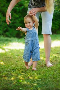 First steps of baby from mother on grass