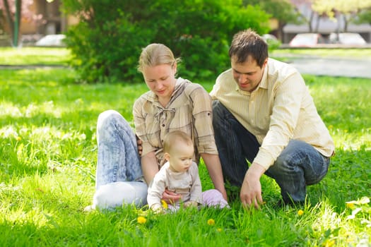 Family with child play in the park on green grass