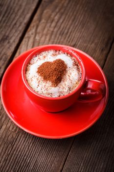 Red cup with cappuccino and heart decoration over foam. Valentine's day cup. Love concept