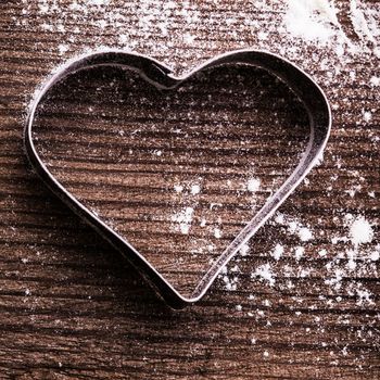 Cookie cutter heart shape on the kitchen table and flour