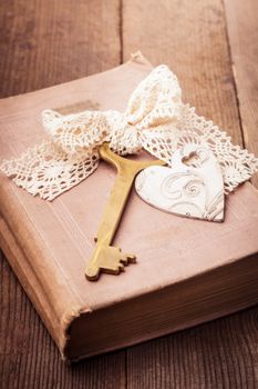 Old book with vintage key and wooden heart, memories concept