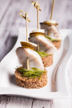 Herring canape with onion, pickled cucumber and dill