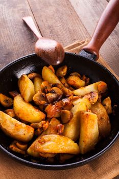 Fried potato and champignons in the cast-iron frying pan