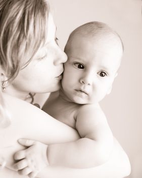 A caucasian mother kissing happy baby, black and white portrait