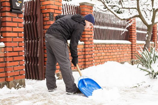 Young man remove snow near the suburban house