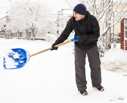Young man remove snow near the suburban house