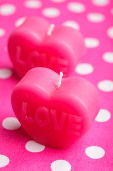 Red scented candle in the shape of heart closeup on the pink background