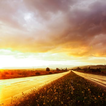 Wet road after rain and sunset over fields