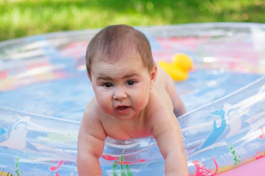 Cute baby in the inflatable pool on grass