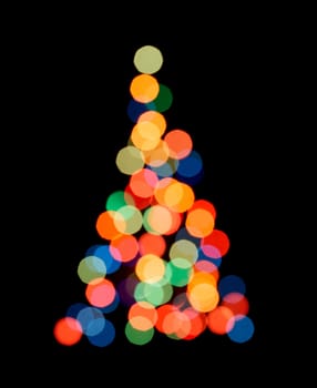 Blurred colorful lights as a silhouette of Christmas tree on black