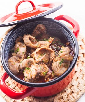 Stewed chicken gizzards in red pan on the mat