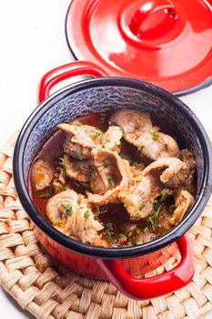 Stewed chicken gizzards in red pan on the mat