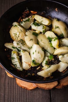 Rustic baked potato with herbs in frying pan