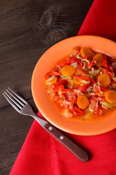 Stewed vegetables on the orange plate and red napkin