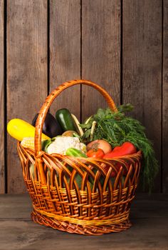 Basket with vegetables and fresh herbs on the wood background with copy space