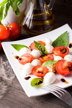 Classic caprese salad: tomato, mozzarella and basil leaves