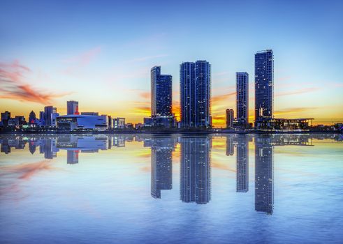 Miami city skyline panorama at dusk with urban skyscrapers over sea with reflection 