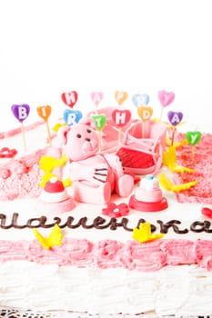 A pink 	
children's birthday cake with "Happy birthday" candles