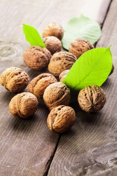 Walnuts with shell and green leaf on the wooden table
