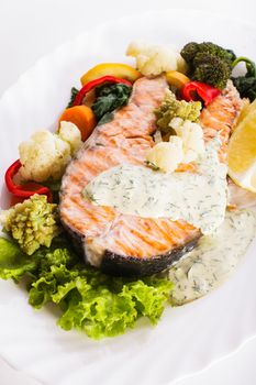 A grilled salmon steak with vegatable and lemon sauce