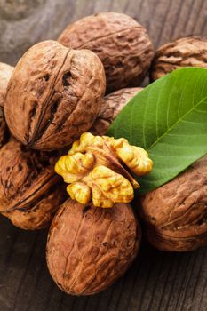 Walnuts with shell and green leaf on the wooden table