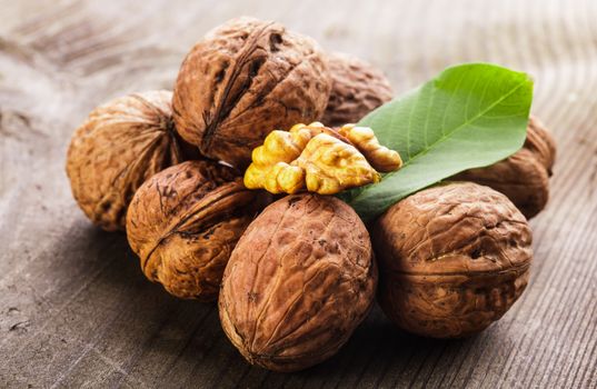 Walnuts with shell and green leaf on the wooden table