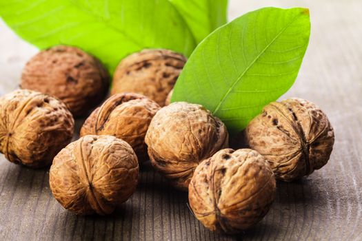 Walnuts with shell and green leaf on the wooden table